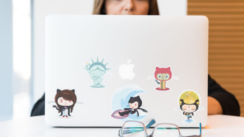 Programista pracujący na laptopie z naklejkami GitHub