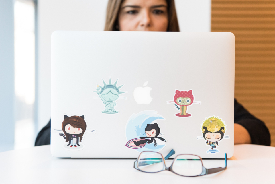 Programista pracujący na laptopie z naklejkami GitHub